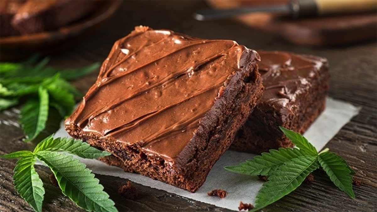 Chocolate brownie surrounded by cannabis leaves